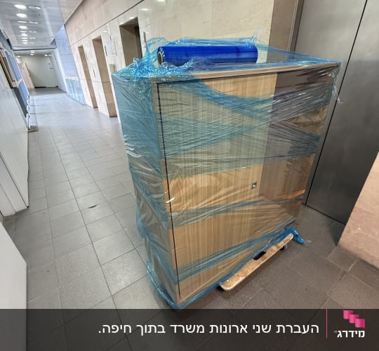 ארון עטוף בניילון כחול על משטח עץ במסדרון